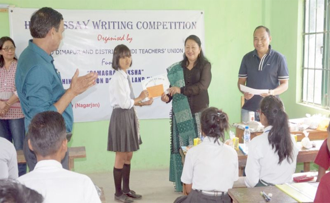 Students receiving encouragement from SI Srinivas,Essay competitions organized at Local Government High School, Students participating in essay competition