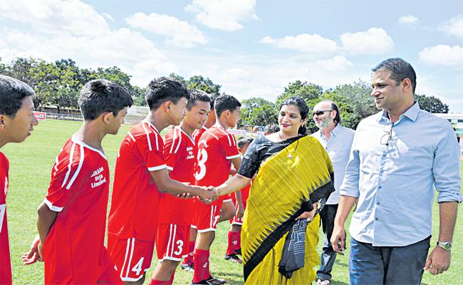 Participants and organizers gathered at a sports event.,Football players with Collector Gautami and Association officers,District collector addressing the audience at a sports event.